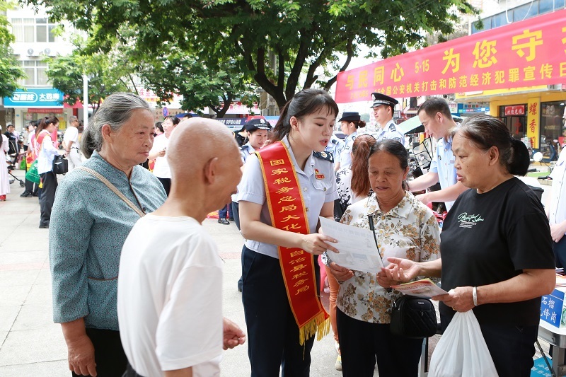 图为大化县税务局红石榴先锋队员在县域铜鼓广场向往来群众宣传社保费缴纳指引(李雅婷摄.jpg